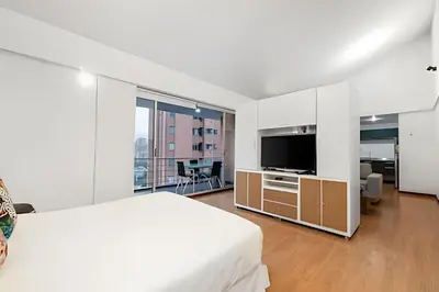 a white bedroom with a large bed and a flat screen tv at Gauss 1205-Serenity Modern Apt/Terrace/Squash/Gym in El Poblado