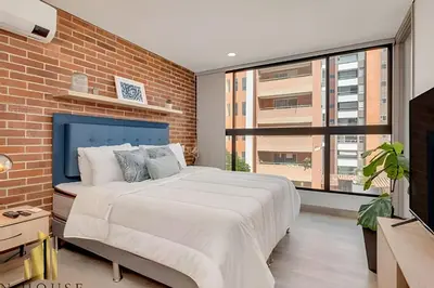 a bedroom with a large bed and a brick wall at Kyux 405 - The Icon of Exclusivity in Laureles in Alpujarra