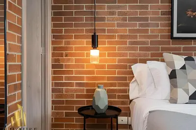 a bedroom with a brick wall with a bed and a lamp at Kyux 408 - The hidden gem of Laureles in Alpujarra