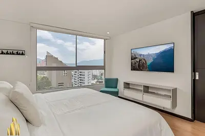 a white bedroom with a bed and a large window at Life 1202 - Pleasant Apt in Poblado with AC in El Poblado