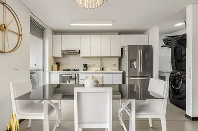 a kitchen with white cabinets and a table and chairs at Life 1202 - Pleasant Apt in Poblado with AC in El Poblado