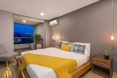 a bedroom with a large bed with a yellow blanket at Life 1603 - Panoramic & Tastefully Decorated Loft in El Poblado