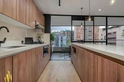 a kitchen with wooden cabinets and a large window at Life 801 - Exclusive & Bright Apt/pool/gym/balcony in El Poblado