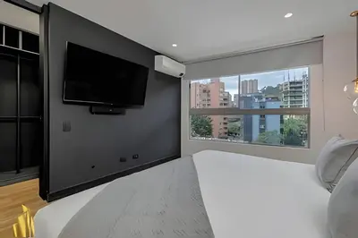 a bedroom with a flat screen tv and a large window at Life 801 - Exclusive & Bright Apt/pool/gym/balcony in El Poblado