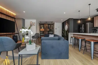 a living room with a blue couch and a kitchen at Life 801 - Exclusive & Bright Apt/pool/gym/balcony in El Poblado