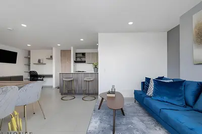a living room with a blue couch and a kitchen at Metropolitan 2226-Familiar Bright Apt/Priv balcony in El Salvador