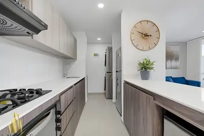a kitchen with white counters and a clock on the wall at Metropolitan 2226-Familiar Bright Apt/Priv balcony in El Salvador