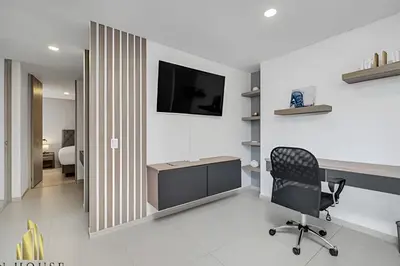 a room with a chair and a television on a wall at Metropolitan 2226-Familiar Bright Apt/Priv balcony in El Salvador