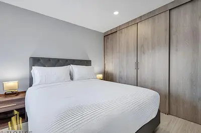 a bedroom with a large white bed and wooden cabinets at Metropolitan 2226-Familiar Bright Apt/Priv balcony in El Salvador