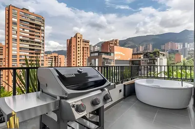 a grill and tub on a balcony with a city at Morph 1101 - Sophisticated & brigh apt/ BBQ in El Poblado