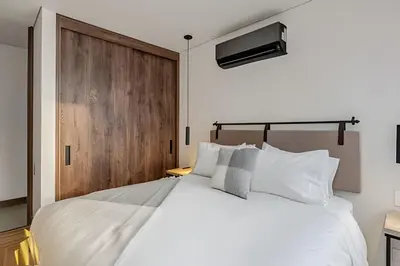 a bedroom with a white bed and a wooden door at Morph 1802 - Stylish Escape in Poblado AC/Jacuzzi in El Poblado