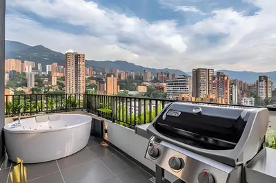 a grill and tub on a balcony with a city skyline at Morph 1802 - Stylish Escape in Poblado AC/Jacuzzi in El Poblado