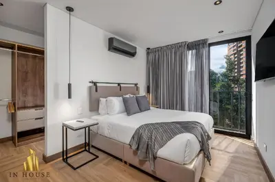 a bedroom with a bed and a large window at Morph 302 - Modern apt high ceilings BBQ/Jacuzzi in El Poblado