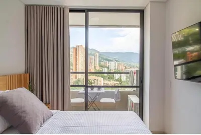a bedroom with a bed and a balcony with a table at Beautiful apartment in Poblado in Medellín