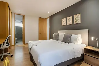 a bedroom with a large white bed and a chair at Santacoloma 407 Apto tranquilo con vistas verdes. AC in El Poblado