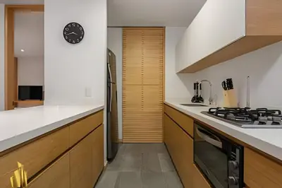 a kitchen with wooden cabinets and a clock on the wall at Santacoloma 407 Apto tranquilo con vistas verdes. AC in El Poblado