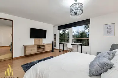 a white bedroom with a tv and a bed at Santiago De Bagatela 401 - Serene apt/sauna & gym in Envigado