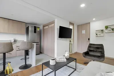 a living room with a tv and a chair and a table at Scala 1901 - Serene apt/balcony/deluxe furniture in Sabaneta