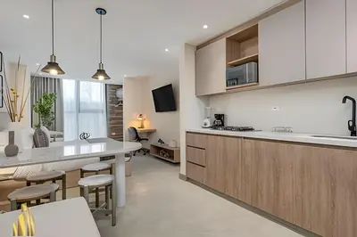 a kitchen with white cabinets and a kitchen island with stools at Solei Loft 202 - Chic Studio with AC in El Poblado