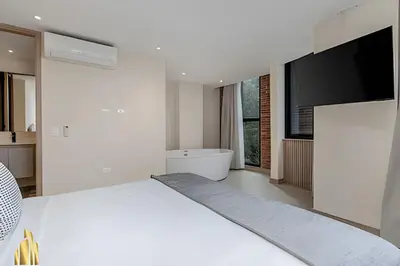 a white bedroom with a large bed and a flat screen tv at Solei Loft 301 - Location/Trendy Jacuzzi Living in El Poblado