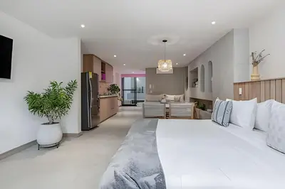 a bedroom with a large white bed and a kitchen at Solei Loft 302 - Elegant Oasis: Loft/Jacuzzi/AC in El Poblado