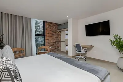 a bedroom with a bed and a desk and a tv at Solei Loft 302 - Elegant Oasis: Loft/Jacuzzi/AC in El Poblado