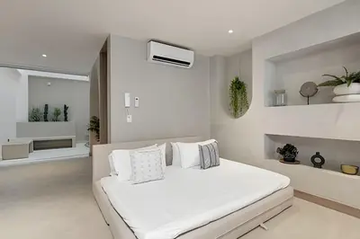 a white bedroom with a bed with white pillows at Solei Loft 302 - Elegant Oasis: Loft/Jacuzzi/AC in El Poblado