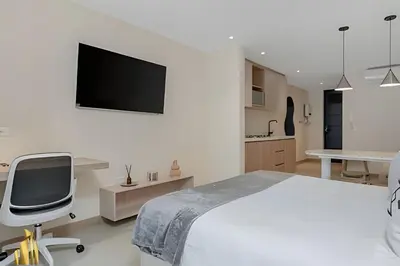a bedroom with a bed and a chair and a tv at Solei Loft 303 - Modern Loft in Poblado with AC in El Poblado