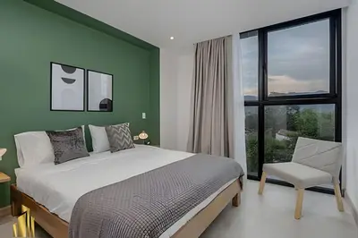 a bedroom with green walls and a bed and a chair at Solei Loft 502 - Calm & cozy in Manila Poblado/AC in El Poblado