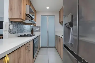 a kitchen with wooden cabinets and a stainless steel refrigerator at Torre 6 Sur - Trendy Loft: Balcony, AC / Poblado in El Poblado