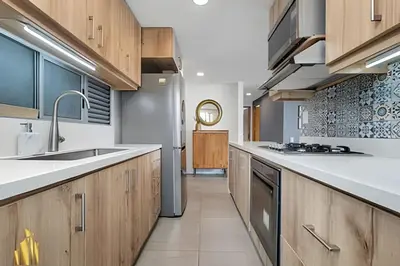 a kitchen with white countertops and wooden cabinets at Torre 6 Sur - Trendy Loft: Balcony, AC / Poblado in El Poblado