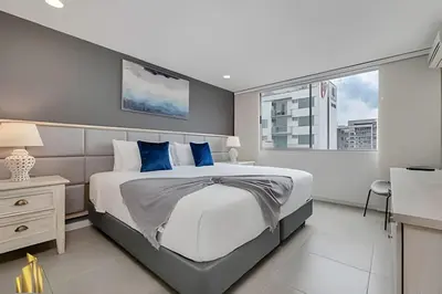 a bedroom with a large bed with blue pillows at Torre 6 Sur - Trendy Loft: Balcony, AC / Poblado in El Poblado