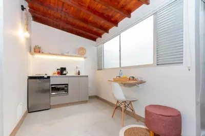 a kitchen with a counter and a table and two windows at Modern Cozy Apt - Laureles -AC - Fast WiFi in Medellín