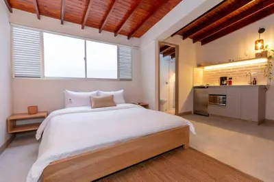 a bedroom with a large white bed and a kitchen at Laureles Apt-Smart locks-Excellent Location-AC in Medellín