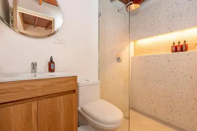a bathroom with a toilet and a sink and a mirror at Laureles Apt-Smart locks-Excellent Location-AC in Medellín
