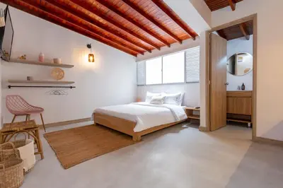 a bedroom with a bed and a chair and a window at Laureles Apt-Smart locks-Excellent Location-AC in Medellín