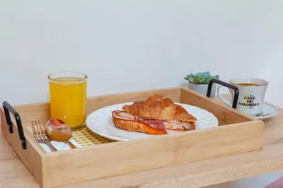 a wooden tray with a sandwich and a glass of orange juice at Spacious Laureles Apt-Smart Lock-Queen Bed-AC in Medellín