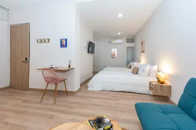 a bedroom with a white bed and a blue couch at Spacious Apt -Laureles -AC -Smart Lock- WiFi in Medellín