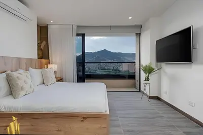 a bedroom with a bed and a flat screen tv at Clase 48 apt1002 - Loft with Panoramic Views and AC in Sabaneta