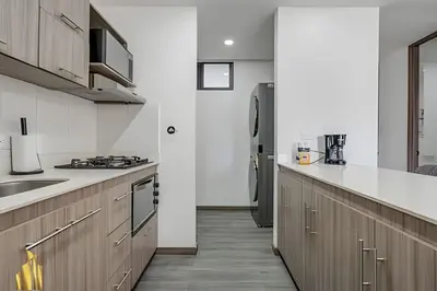 a kitchen with wooden cabinets and a refrigerator at Clase 48 apt1002 - Loft with Panoramic Views and AC in Sabaneta