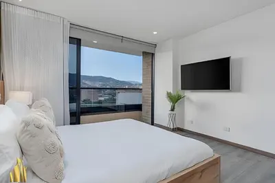 a bedroom with a large bed and a flat screen tv at Clase 48 apt1002 - Loft with Panoramic Views and AC in Sabaneta