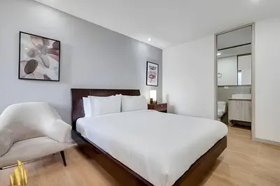a bedroom with a large white bed and a chair at Class 48 apto. 1303 - Luminoso / Vistas / Balcón in Sabaneta