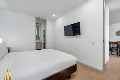 a white bedroom with a bed and a tv on the wall at Class 48 apto. 1303 - Luminoso / Vistas / Balcón in Sabaneta