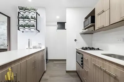 a kitchen with white walls and wooden cabinets at Class 48 apto. 1401 - Panorámico para nómadas digital/AC in Sabaneta
