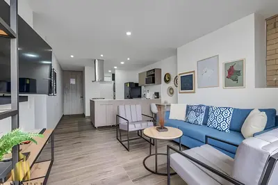 a living room with a blue couch and a kitchen at Class 48 apto. 1404 - Vistas modernas de la ciudad / AC in Sabaneta