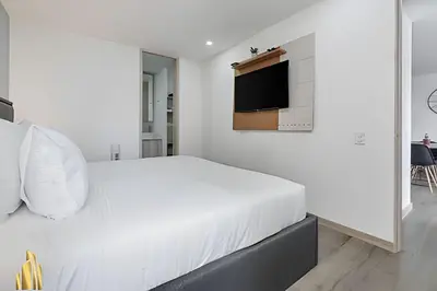 a white bedroom with a bed and a tv on the wall at Class 48 apto. 1503 - Tranquilidad moderna/Balcón priv in Sabaneta