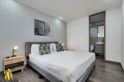 a bedroom with a large white bed and a table at Class 48 apto. 1603 - Sophisticated apt/panoramic views in Sabaneta