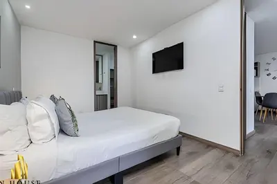 a white bedroom with a bed and a television at Class 48 apto. 1603 - Sophisticated apt/panoramic views in Sabaneta