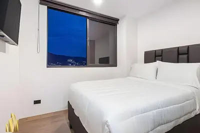 a bedroom with a white bed and a window at Class 48 Apt. 2203 - Apt moderno y acogedor balcón priv in Sabaneta