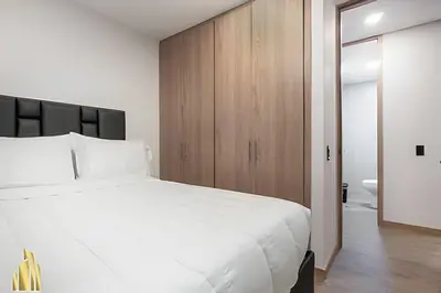 a bedroom with a large white bed and wooden cabinets at Class 48 Apt. 2203 - Apt moderno y acogedor balcón priv in Sabaneta
